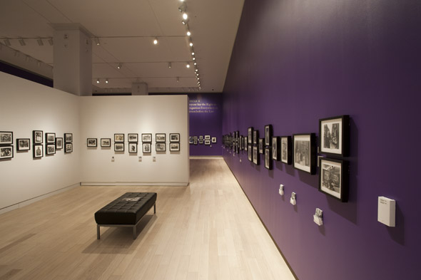 Inside gallery with long purple wall and framed black and white prints 